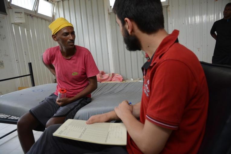 John lors d'une consultation avec un médecin MSF au centre de détention de Gharyan al-Hamra. Il avait la tuberculose et avait été enfermé dans un conteneur pendant des mois sans accès aux soins de santé. Libye. 2019.
 © Jérôme Tubiana/MSF