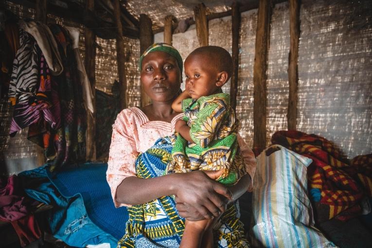 Sifa tient sa fille Tamuriza dans ses bras, assise dans leur tente faite de bois et de bâches sur le site de déplacés de Katale, dans le territoire de Masisi.&nbsp;
 © MSF/Laora Vigourt