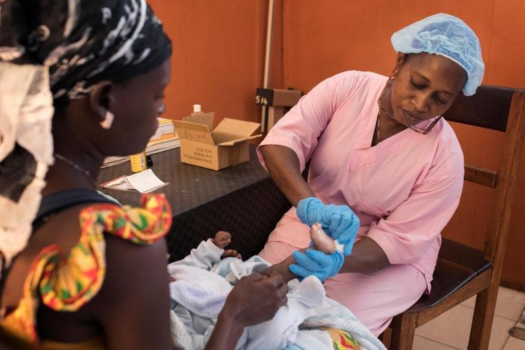 Une sage-femme du ministère guinéen de la Santé effectue un test de diagnostic précoce du nourrisson sur un bébé né d'une mère séropositive. Conakry, Guinée.
 © Albert Masias/MSF