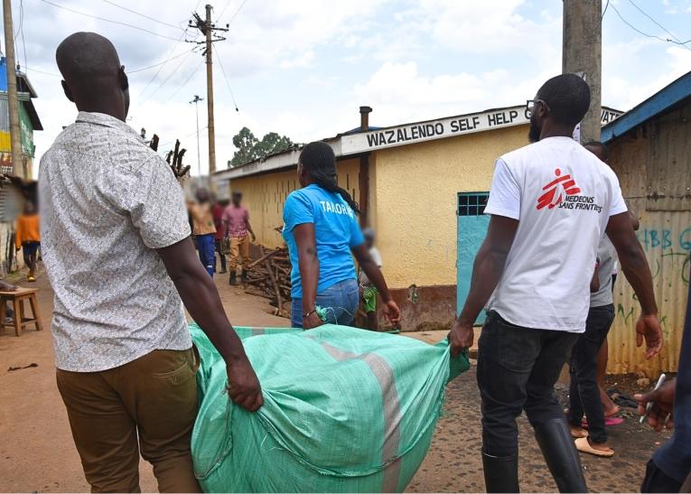 Des membres des équipes MSF, accompagnés d'habitants, transportent des vêtements destinés aux enfants de moins de dix ans.
© MSF/Lucy Makori