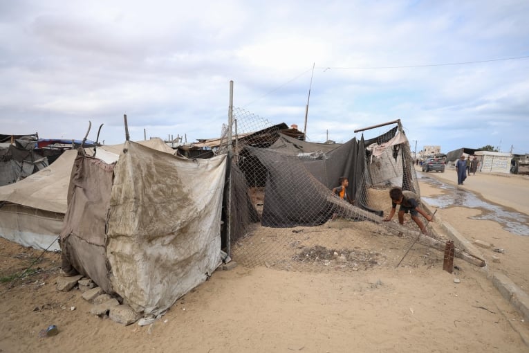 Des enfants jouent sur un enchevêtrement de câbles tombés dans une rue à côté de la tente où leur famille a trouvé refuge à Mawasi, Khan Younès. En raison du manque d'aires de jeux sécurisées, les enfants des camps de déplacés sont souvent exposés à des environnements dangereux et à des débris. Gaza, octobre 2025
 © Motasem Abu Aser/MSF
