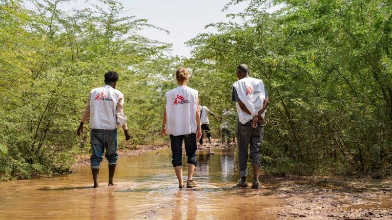 Les membres d'une équipe MSF marchent dans la boue pour franchir une route inondée.
 © Paula Casado Aguirregabiria/MSF
