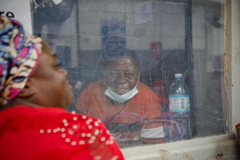Victoire, atteint du virus Ebola, passe ses journées au centre de traitement Ebola (CTE) de Kitatumba, à Butembo, en attendant de pouvoir sortir, son état de santé s’améliorant. Son épouse, Kasoki, vient chaque jour pour le soutenir et veiller sur lui.
 © Elio Parfait/MSF