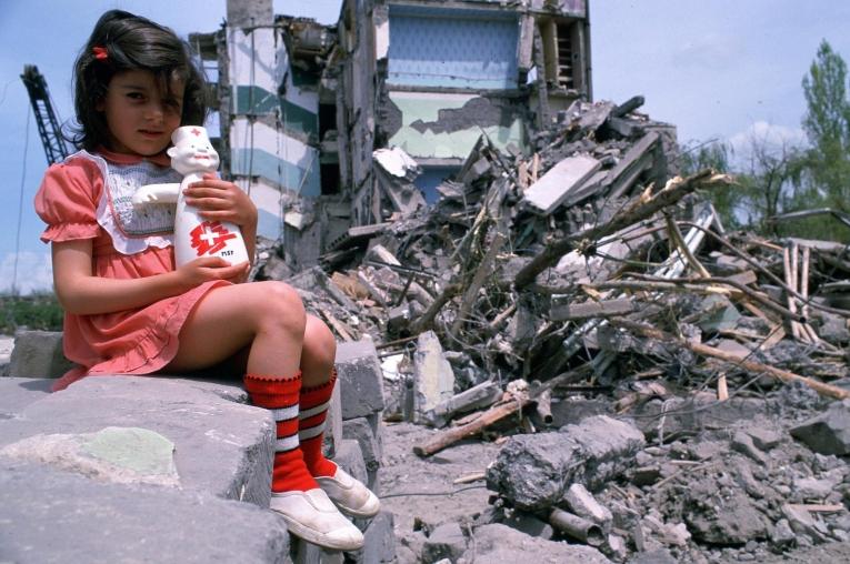 Une petite fille devant les décombres d'un bâtiment de Gyumri, à la suite du tremblement de terre de 1988.