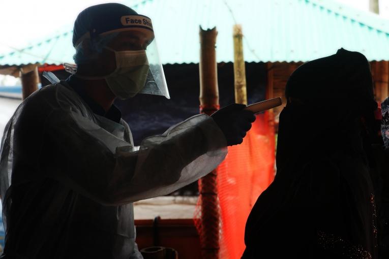 Un membre du personnel MSF vérifie la température d'une femme à l'hôpital de Goyalmara à Cox’s Bazar pour lutter contre la Covid-19.