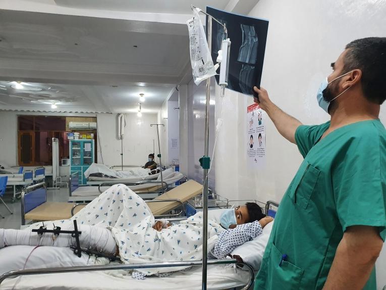 Dans le centre de traumatologie de Kunduz, un infirmier examine la radio d'un patient qui a subi une fracture de la partie supérieure et inférieure de la jambe suite à une explosion.