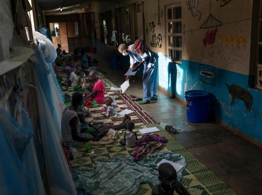 Un membre du personnel médical de MSF remet des papiers à une femme dans le couloir où ont été installés certains patients, faute de place dans l'hôpital. Octobre 2021.