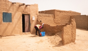 Un migrant lave son linge devant la maison qu'il loue avec d'autres dans un ghetto d'Agadez. Celles et ceux qui passent par Agadez luttent pour trouver un emploi afin de gagner de l'argent pour avoir un endroit où dormir, de la nourriture, et pour continuer leur voyage. 