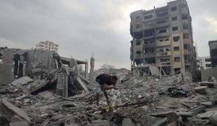 Un homme boit au milieu des décombres à Gaza.