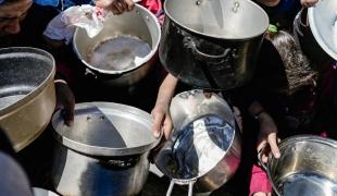 Des enfants tenant leurs pots vides dans une cuisine communautaire dans le nord de Gaza, février 2025 