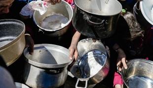 Des enfants tenant leurs pots vides dans une cuisine communautaire dans le nord de Gaza, février 2025 