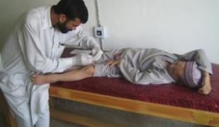Centre de santé MSF de Darband. Un technicien de laboratoire effectue un prélèvement sur Basit un jeune patient.