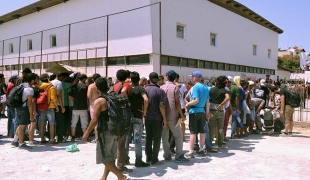 Les migrants font la queue à l'extérieur du stade de Kos en attendant d'être enregistrés par la police grecque.