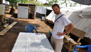 Pascal devant le plan de la structure de prise en charge de l'Ebola à Guéckédou en Guinée.