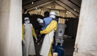 Luis Encinas est un des spécialistes d'Ebola chez MSF. Il tient dans ses bras un garçon de sept ans atteint par la maladie. Centre de traitement d'Ebola de Butembo. République démocratique du Congo. 2018.