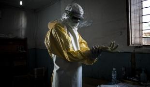 Un travailleur de santé MSF revêt son équipement de protection personnel avant d'entrer dans la zone à risque du centre d'isolement Ebola de Bunia. Il va procéder à une évaluation de l'état des patients. Novembre 2018. République démocratique du Congo.