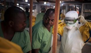 Un travailleur de santé revêt son masque avant d'entrer dans la zone à risque d'un centre de traitement Ebola. Novembre 2018. République démocratique du Congo. 