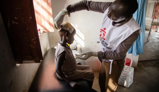 Un membre du personnel MSF examine une jeune fille blessée à la tête dans l'hôpital d'Ulang, dans le nord-est du Soudan du Sud. 2019.