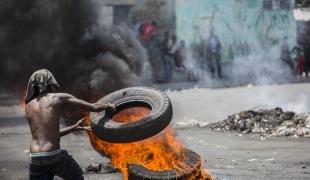 Un manifestant bloque une rue de Port-au-Prince le 13 juin 2019, lors d'une manifestation réclamant le départ du président Jovenel Moïse. Depuis des mois, le pouvoir d'achat des Haïtiens est en baisse constante avec la dévaluation de la monnaie nationale et les prix du carburant ont augmenté. 