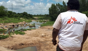 Alphonse Elogo, expert MSF en eau et assainissement, observe un point d'eau potentiellement contaminée dans un quartier du district de santé de Pitoa. 2019. Cameroun. 