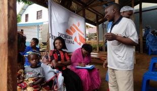 Joseph MbokaniI Kambale, l’un des agents de sensibilisation déployés par le dispositif national de réponse à Ebola, répond aux questions des participants. Les craintes et les rumeurs découragent de nombreuses personnes de se faire vacciner. République démocratique du Congo. 2019. 