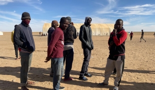 Un groupe de jeunes hommes attendant pour recevoir de la nourriture à Assamaka, après avoir été expulsés d'Algérie. Niger. Mars 2021.