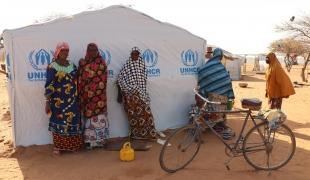 Des femmes se tiennent près d'une tente dans un site de personnes déplacées de la ville de Gorom Gorom. Burkina Faso. 2021. 