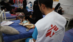 Un membre des équipes MSF de l'hôpital d'Abs, auprès d'un enfant âgé de 3 mois souffrant de malnutrition. Yémen. 2020.