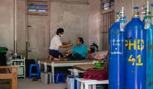 Un membre des équipes MSF au chevet d'une patiente touchée par la Covid-19, dans la clinique MSF de l'État de Kachin. Octobre 2021. Myanmar.