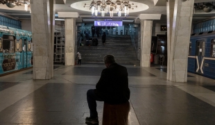 Un homme est assis sur un banc dans le métro. Autour de lui, des wagons où vivent désormais des personnes qui fuit les bombardements à Kharkiv. 11 avril 2022. Ukraine.