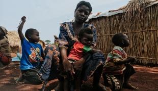 Olga et ses enfants posent devant leur abri du camp de personnes déplacées de Bogouyo. République centrafricaine. 2022.