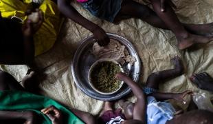 Bria et ses enfants mangent sous le porche à l'extérieur de leur maison.