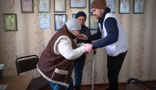 Un médecin MSF aide une patiente atteinte de diabète à se lever. Ukraine. 2022.