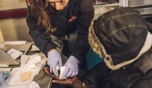 Une infirmière MSF prodigue des soins à la main d’une personne exilée, à Calais, dans le nord de la France. 