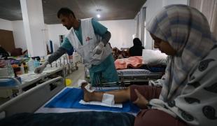 Vue d'une salle d'hospitalisation de l'hôpital indonésien de Rafah avec un membre des équipes MSF et une patiente victime d'une explosion. 