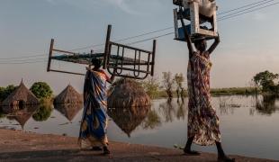 Des femmes transportent des meubles et des marchandises dans une zone inondée de l’État d’Unity.