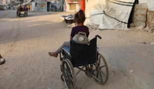 Une enfant près d'un fauteuil roulant qu'elle utilise pour transporter des jerricans d'eau, dans la ville de Gaza, en raison de la destruction systématique des infrastructures hydrauliques par Israël.