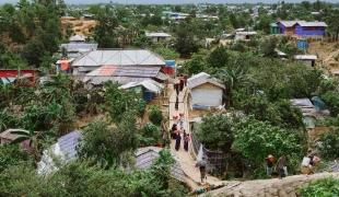Des réfugiés rohingyas retournent à pied dans un camp, chargés de provisions provenant d'un point de distribution.