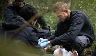 Un secouriste soigne les blessures d'une personne migrante, dans la forêt de Bialovèse en 2024.