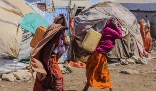 Des femmes transportent des bidons alors qu'elles reviennent du point de distribution d'eau du camp de déplacés de Banban, à Baidoa, en Somalie.