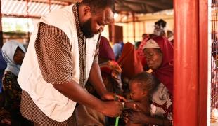Un membre du personnel de MSF mesure la circonférence du bras à mi-hauteur de Maniru, âgé de 2 ans, au centre de nutrition thérapeutique ambulatoire situé dans l'État de Kebbi, au nord-ouest du Nigeria.