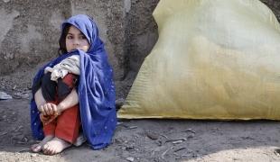 Une petite fille assise près des objets de première nécessité que sa famille a reçu via une distribution de MSF à Peshawar au Pakistan en 2009.