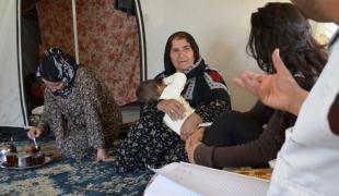 Invités dans la tente Shihab et Aala reçoivent du thé en présence de trois générations d'une même famille. Ils discutent de l'importance de l'alimentation et de l'exercice avec Fatima une réfugiée syrienne de 60 ans.