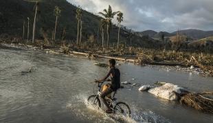 Un garçon roule avec son vélo sur la route inondée après le passage de l’ouragan Matthew. Port Salut sud ouest d’Haiti.