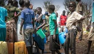Dans le camp de Palorinya des réfugiés viennent chercher de l'eau alors que le camion citerne est embourbé. La saison des pluies risque de rendre l'approvisionnement en eau potable difficile.