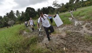 Les équipes de MSF et de Matternet traversent des champs boueux après avoir effectué des tests de vol avec les drones.