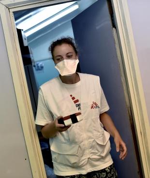 La responsable de laboratoire de MSF, Lise Marchand, entre dans le laboratoire après avoir recueilli l'échantillon d'expectoration du drone à l'extérieur.