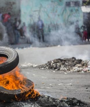 Un manifestant bloque une rue de Port-au-Prince le 13 juin 2019, lors d'une manifestation réclamant le départ du président Jovenel Moïse. Depuis des mois, le pouvoir d'achat des Haïtiens est en baisse constante avec la dévaluation de la monnaie nationale et les prix du carburant ont augmenté. 