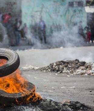 Un manifestant bloque une rue de Port-au-Prince le 13 juin 2019, lors d'une manifestation réclamant le départ du président Jovenel Moïse. Depuis des mois, le pouvoir d'achat des Haïtiens est en baisse constante avec la dévaluation de la monnaie nationale et les prix du carburant ont augmenté.