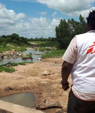 Alphonse Elogo, expert MSF en eau et assainissement, observe un point d'eau potentiellement contaminée dans un quartier du district de santé de Pitoa. 2019. Cameroun. 